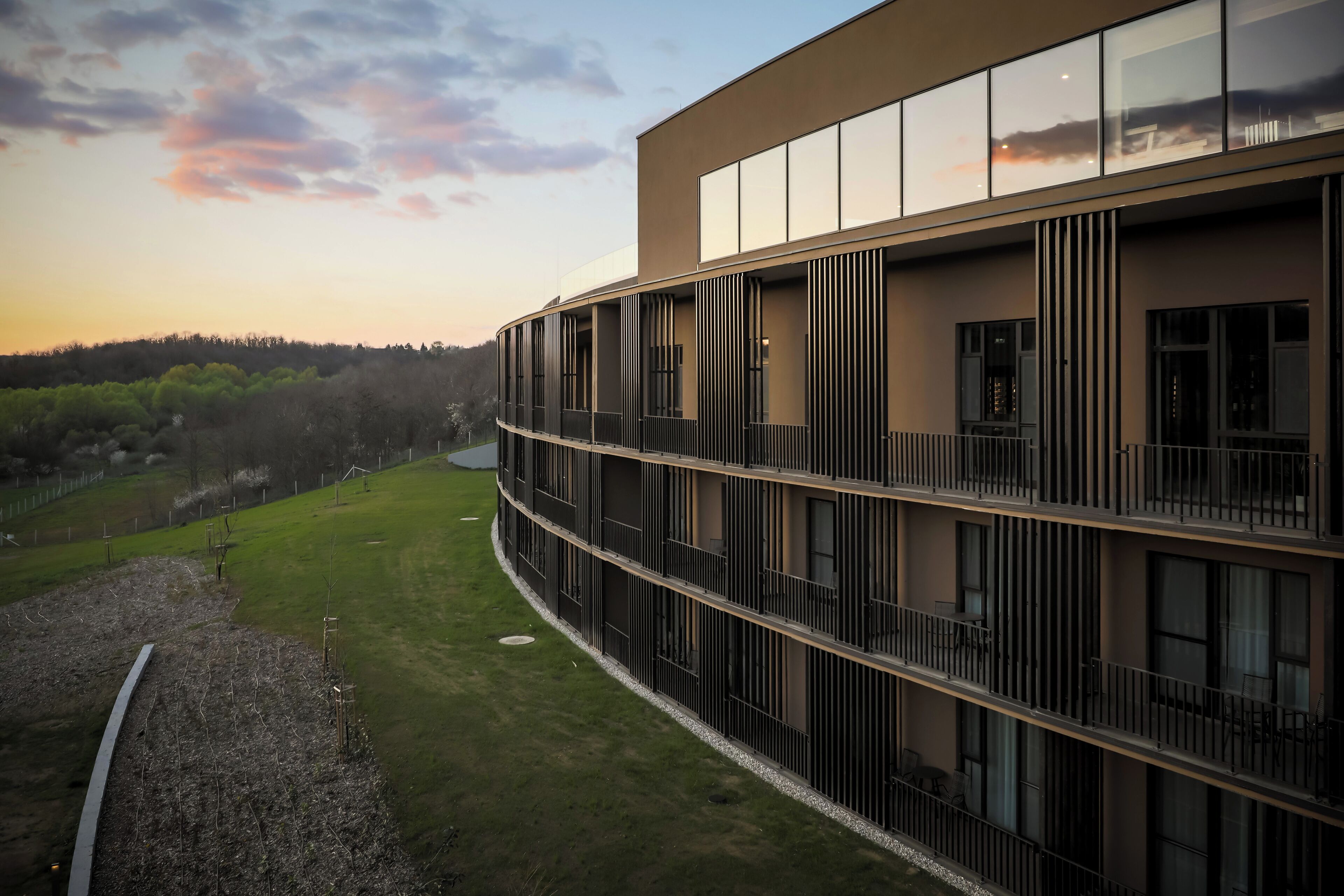 A modern building with multiple floors, large windows, and balconies.