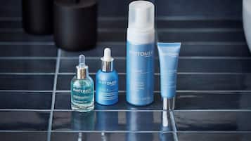 A bathroom with four skincare products from Phytomer on a tiled floor.