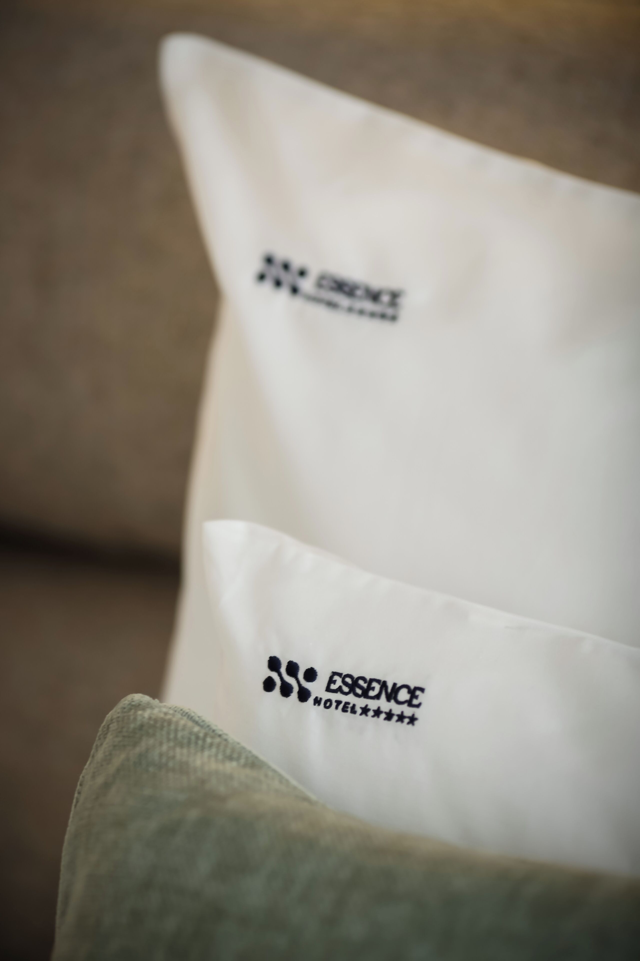 Ein Kissen mit dem Logo und dem Namen des Essence Hotels.