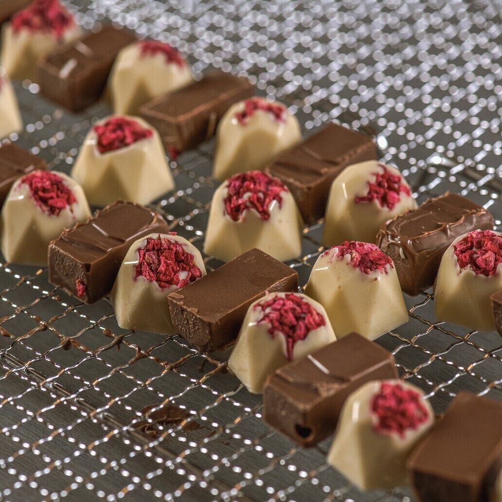 Une sélection de chocolats présentée sur une étagère métallique.