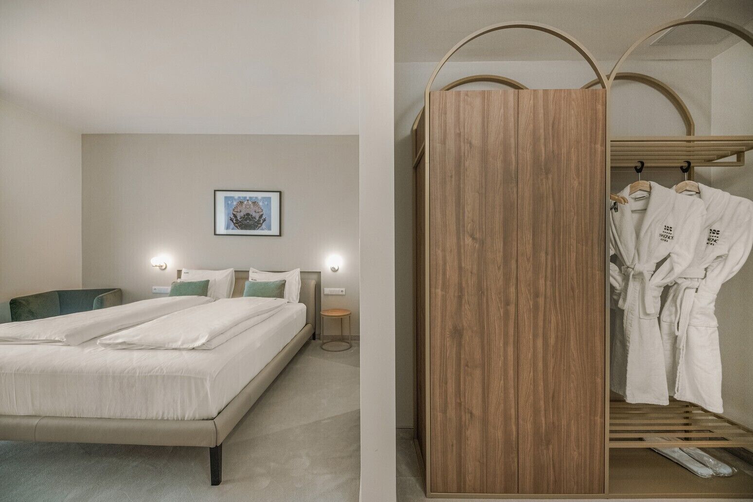 Ett modernt hotellrum med en stor säng, sängbord och en garderob i trä med plats för att hänga kläder.