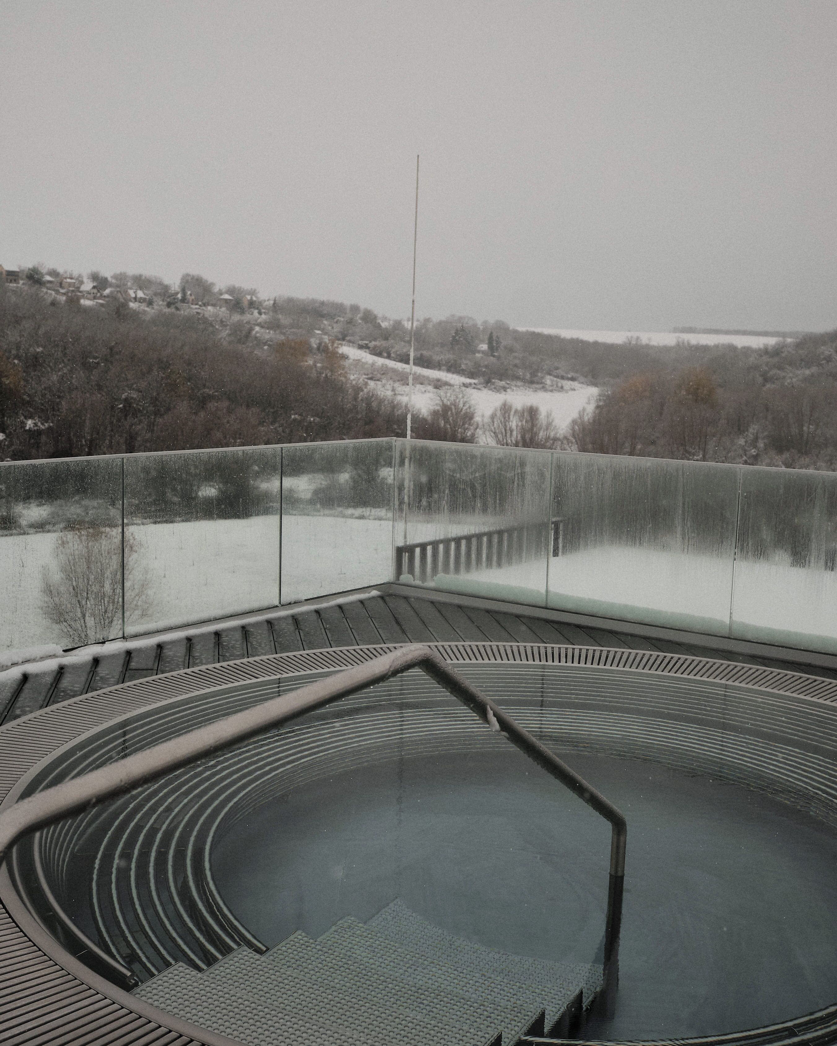 A circular outdoor area with a metal railing, surrounded by snow-covered landscape and trees.