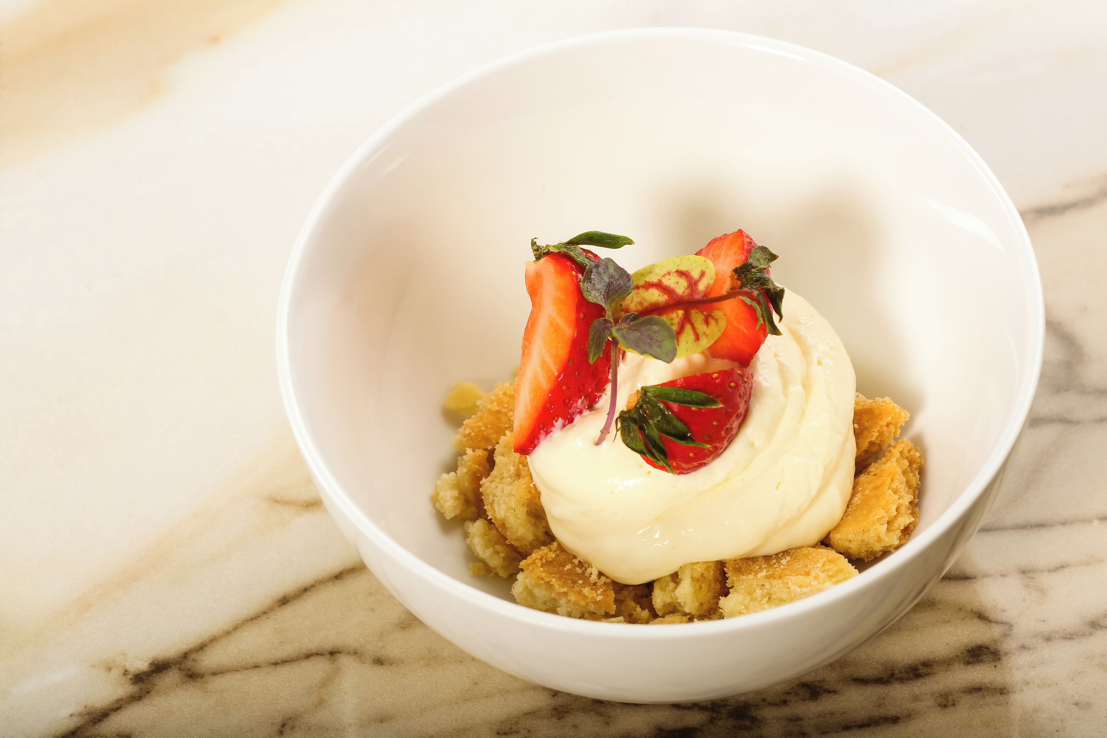 A dessert in a white bowl on a marble surface.