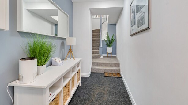 A hallway with a white console table, a lamp, and a plant. There is a staircase leading to another level. - Apartment with castle view (Alnwick)