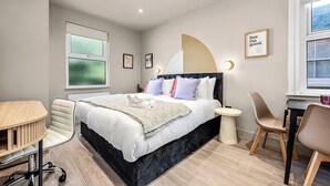 A modern bedroom with a bed, a desk, a chair, and a small table.
