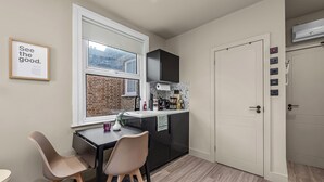 A compact kitchen with a window, a dining area with two chairs, and a door with a control panel.