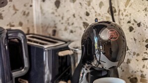 A kitchen counter with a coffee machine, a sugar container, a mug, and a spoon.