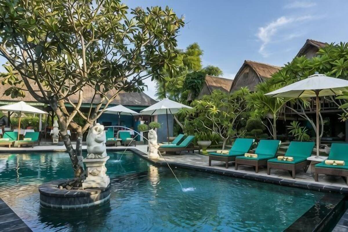 A pool area with lounge chairs, umbrellas, and a decorative fountain.