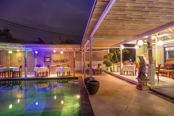 An outdoor pool area with a covered seating area and a dining space. - Nanuk's Bungalows (Bali)
