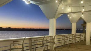 Eine Terrass mit Stühlen und Blick auf das Wasser im Abendlicht.