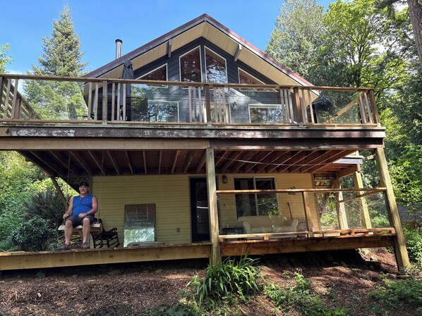 A two-story cabin with a balcony, a covered porch, and a wooden deck. - Cozy, secluded 3 bedroom, 2 bathroom + loft home.Where the sea and forest meet (Sooke)