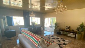 A spacious living area with a large sofa, a chandelier, and a checkered rug.
