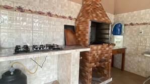 A kitchen with a brick oven, gas stove, and tiled backsplash.