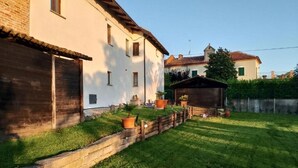 Un bâtiment blanc avec une clôture en bois et une petite construction en bois dans la cour.