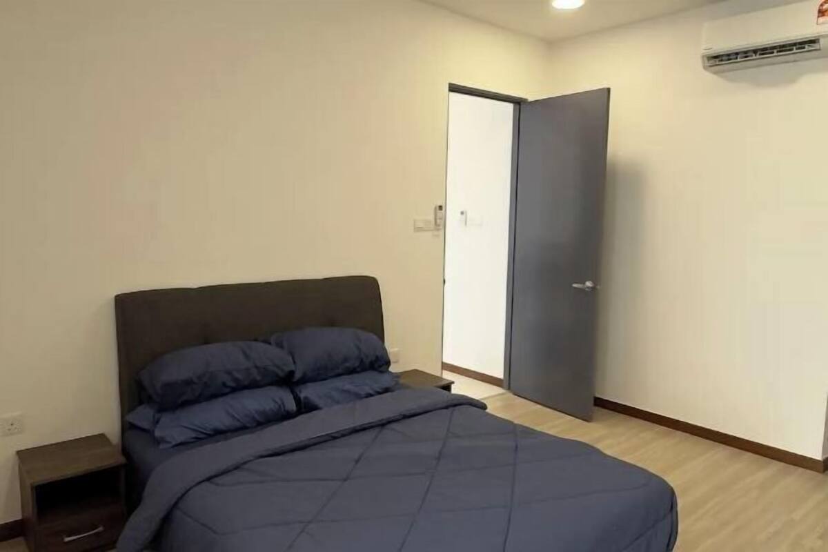 A bedroom with a bed, a nightstand, and an open door to another room.