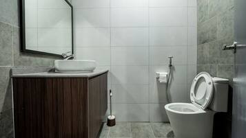 Et badeværelse med en trækommode, en hvid vask, et toilet og et spejl.