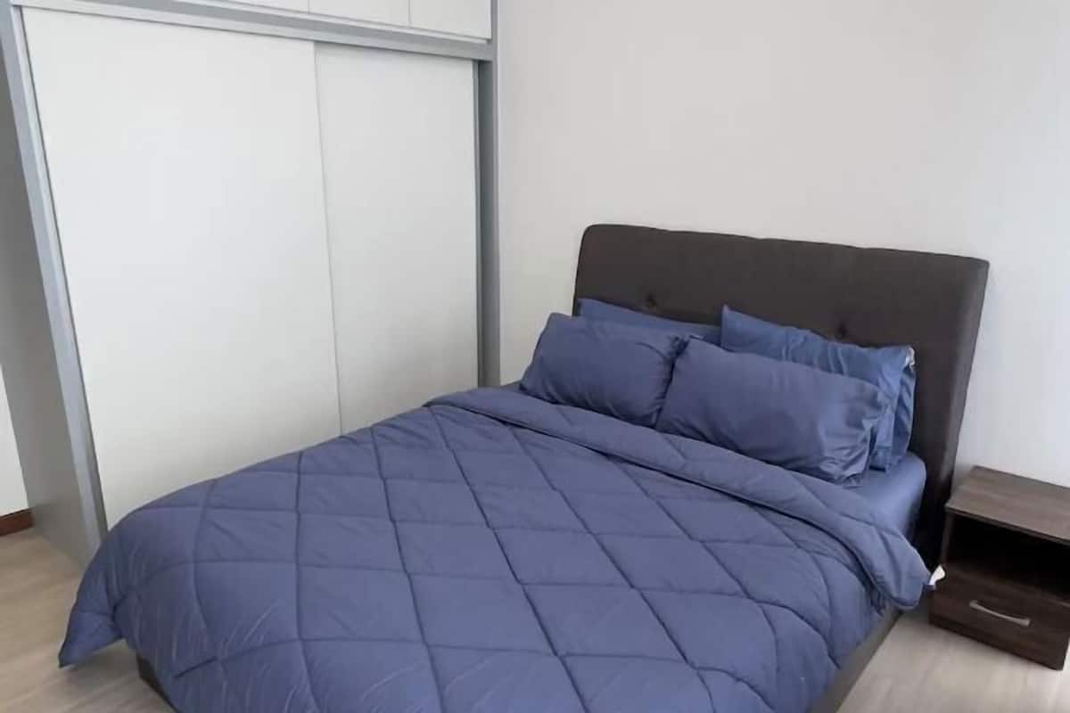 A bedroom with a bed, a nightstand, a wardrobe, and a wall.