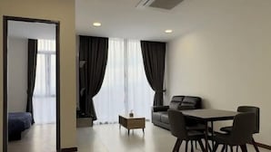 A modern living room with a dining area, featuring a sofa, a coffee table, and a dining table with chairs. - Apartments @ Podium Kuching (Kuching)