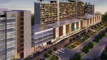 A modern building with multiple floors, large windows, and a parking area with cars.