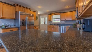 Una cocina con encimeras de granito, electrodomésticos de acero inoxidable, armarios de madera e iluminación empotrada.