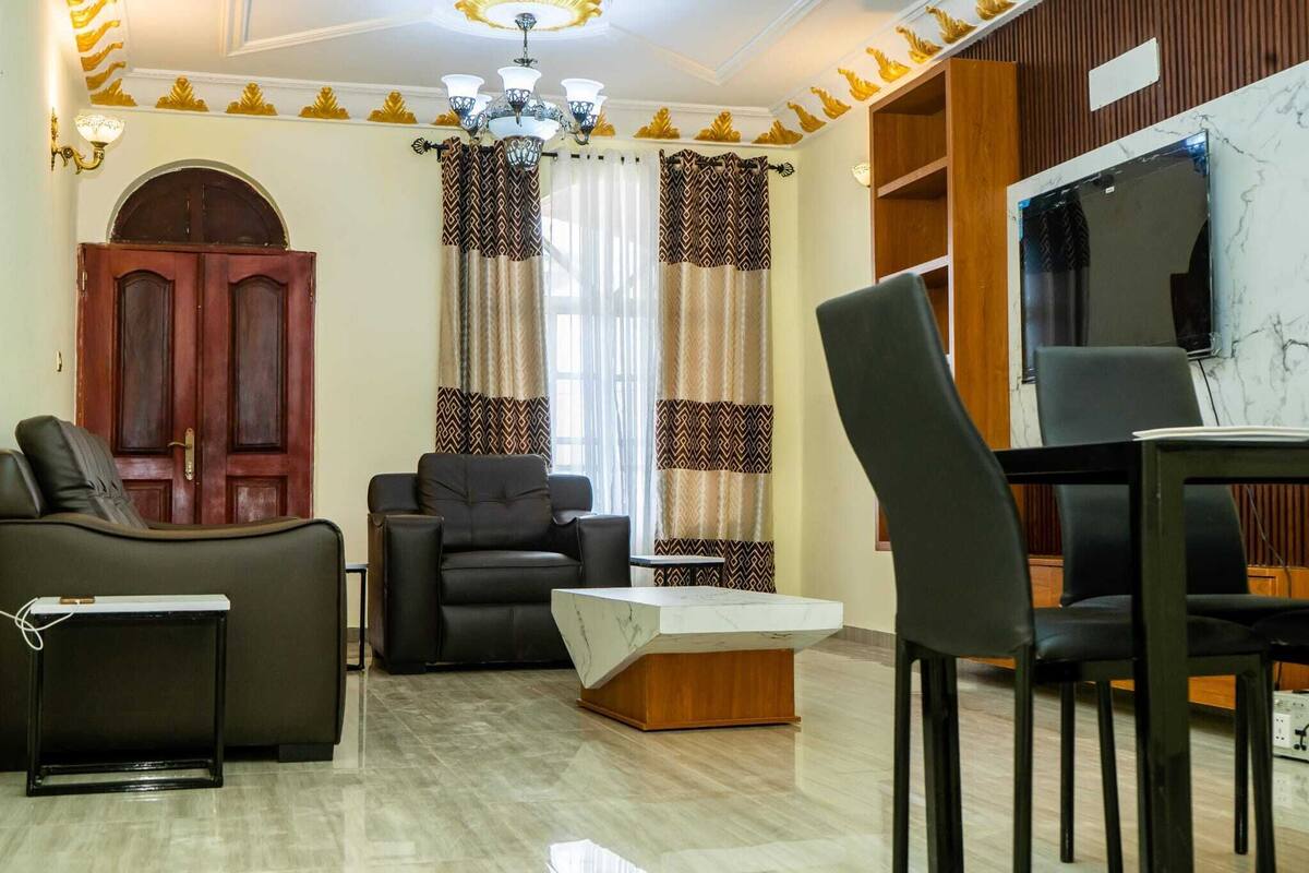 A living room with a sofa, two armchairs, a coffee table, and a TV.