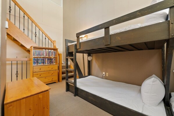 A bunk bed room with a wooden staircase and a bookshelf.