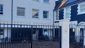 A gated residential area with a white building and a black building with a dark roof. - Number Four  (Brighton)