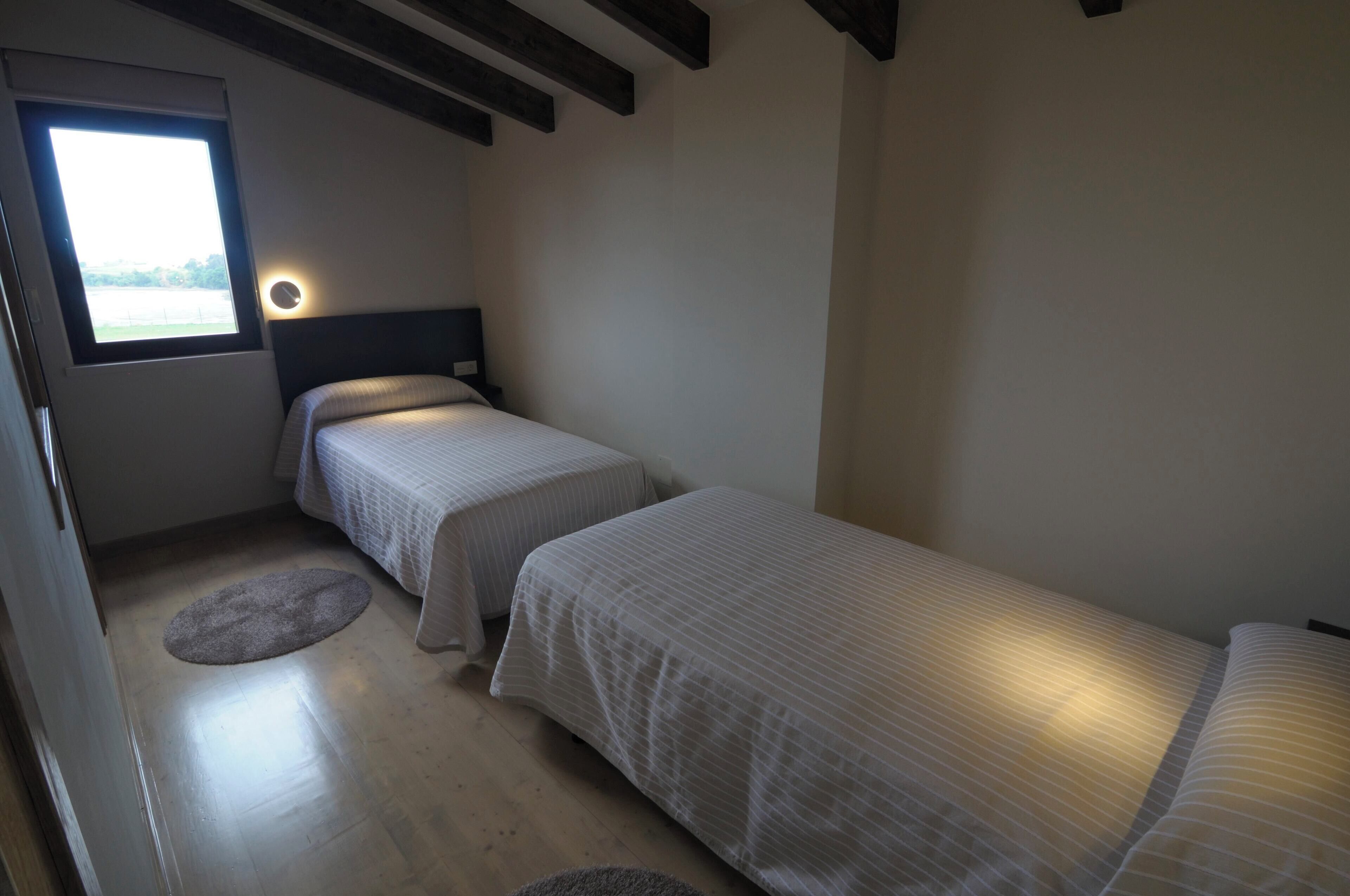 Un dormitorio pequeño y acogedor con dos camas individuales, una ventana con vistas y un reloj de pared redondo.
