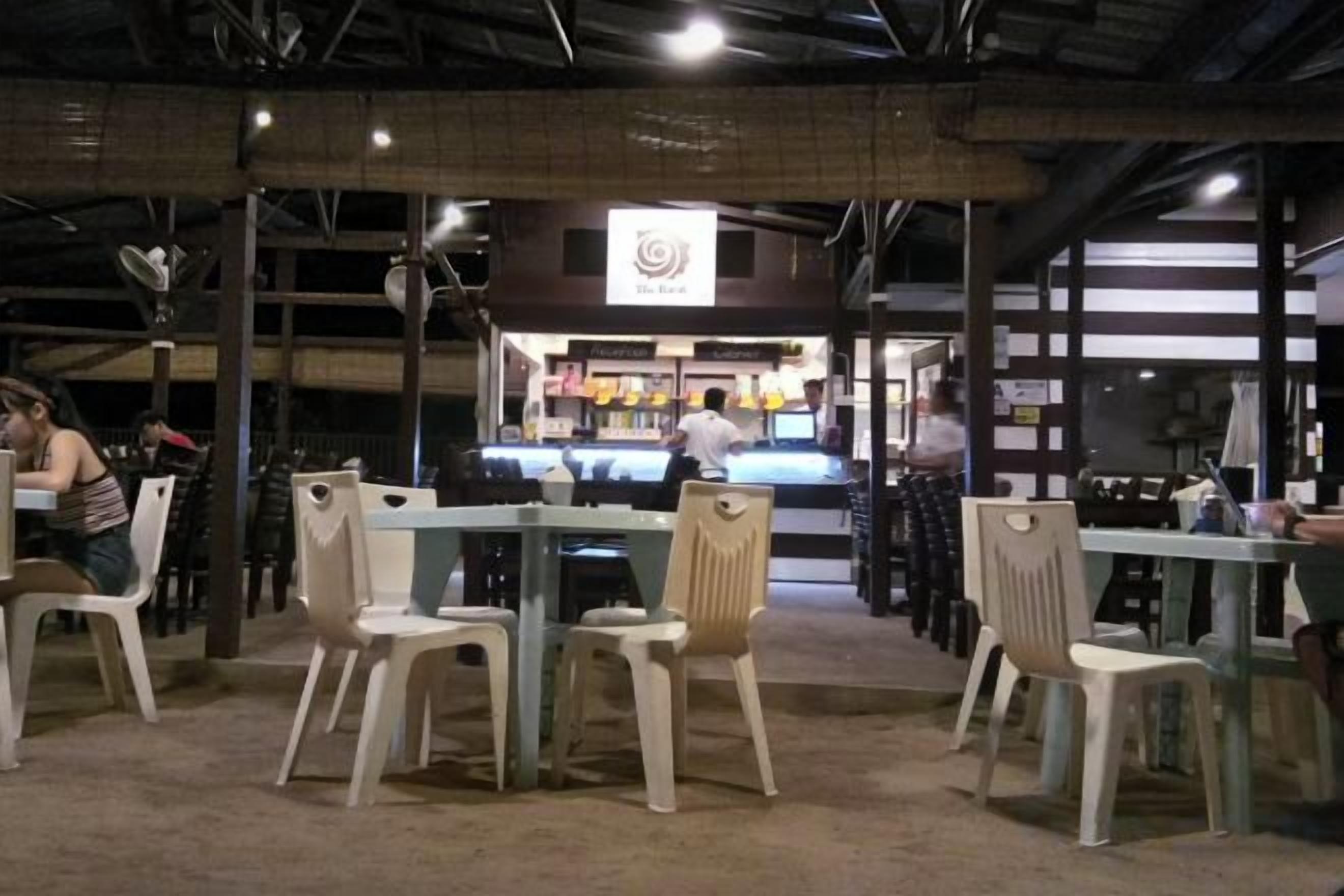 An indoor dining area with tables and chairs, a counter with a menu, and a sign above the counter.