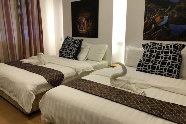 Une chambre d’hôtel avec deux lits, chacun étant agrémenté d’une couvre-lit à motifs, d’un oreiller et d’une tête de lit.