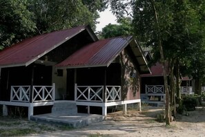 Un chalet rustique doté d’une véranda, entouré d’arbres.