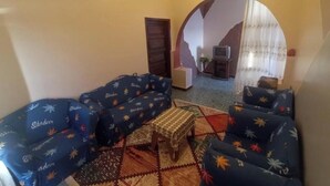 Ein Wohnzimmer mit blauen Sofas, einem kleinen Holztisch und einem gemusterten Teppich.