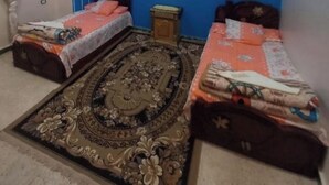 Ein Schlafzimmer mit zwei Einzelbetten, einem Deckenventilator, einem gemusterten Teppich und einer blauen Akzentwand.