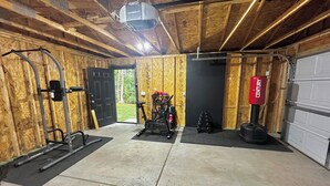 A gym with exercise equipment, a door leading outside, and a garage with a Century-branded tire. - Double Up In Delano-by Dtwn Stadium&ballpark Arena (Wichita)