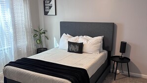 A bedroom with a bed, a ceiling fan, a bedside table, a potted plant, and a framed quote on the wall. - Double Up In Delano-by Dtwn Stadium&ballpark Arena (Wichita)