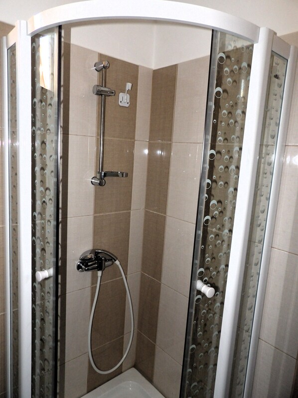 A glass-enclosed shower with a handheld showerhead and a wall-mounted faucet. - Pensiunea Pizza House (Hangu)