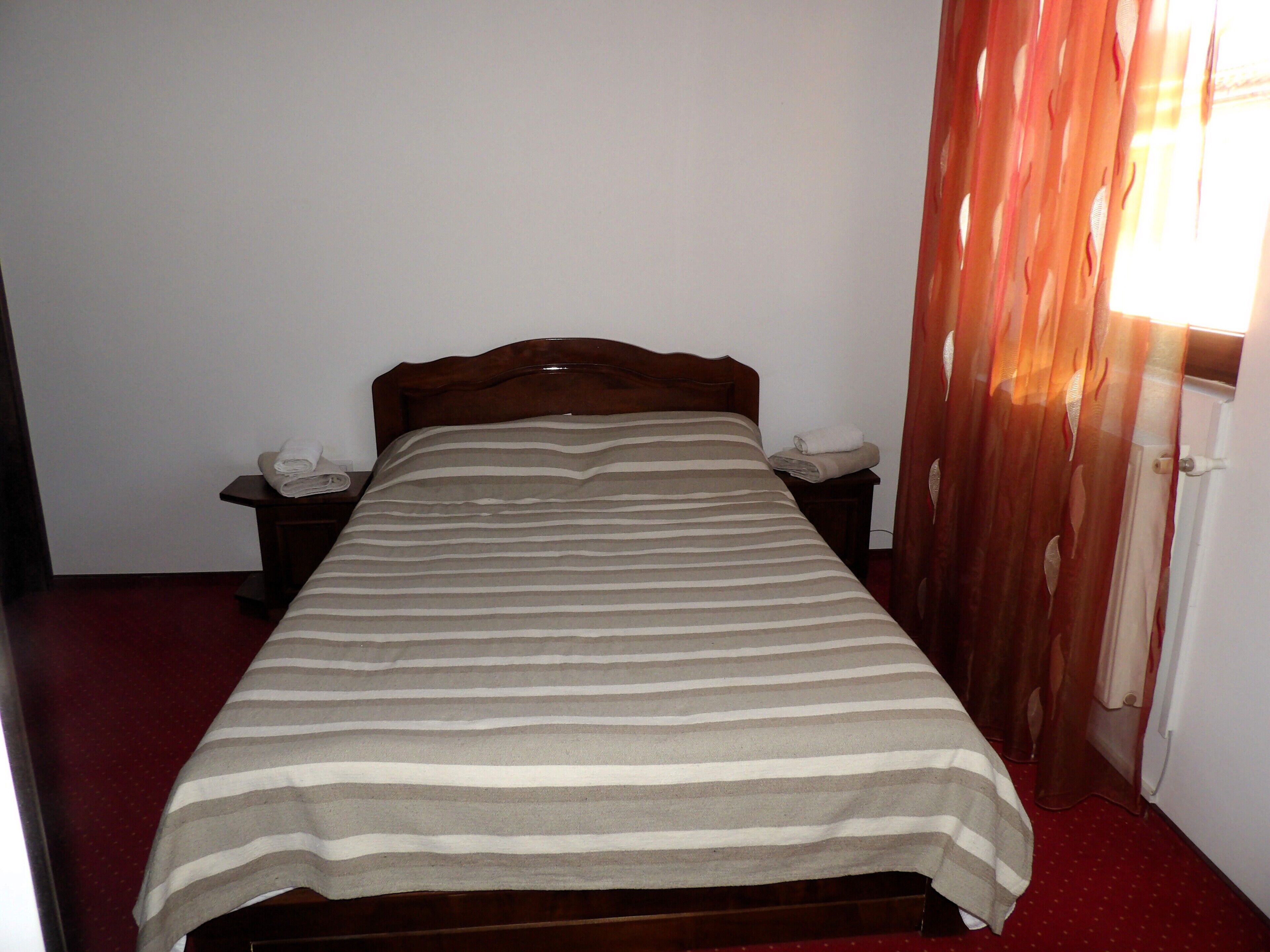 A single bed with a striped bedspread, two bedside tables, and a nightstand with a lamp.