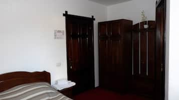 A bedroom with a bed, a wooden wardrobe, and a red carpet.