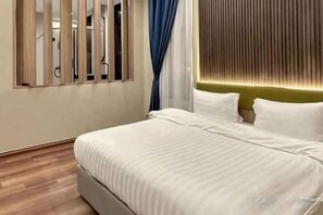 Una habitación de hotel con una cama, un ventanal con persianas y una lámpara fijada a la pared.