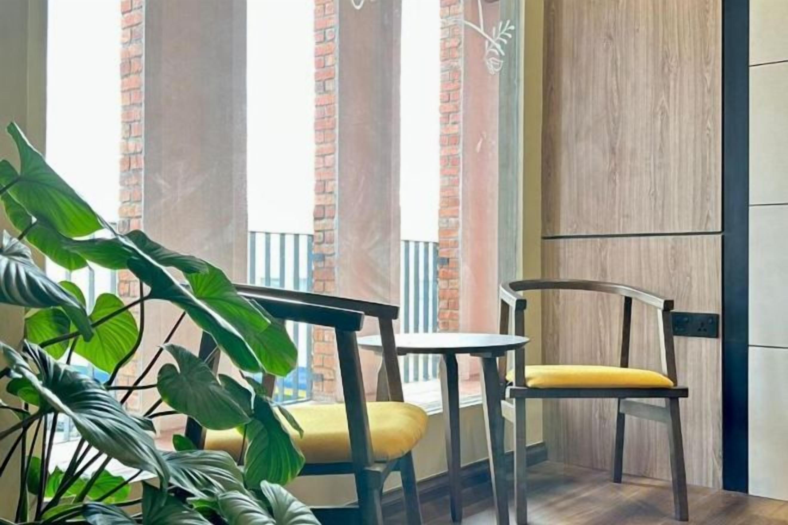 A room with a balcony, a chair with a yellow cushion, and a potted plant.
