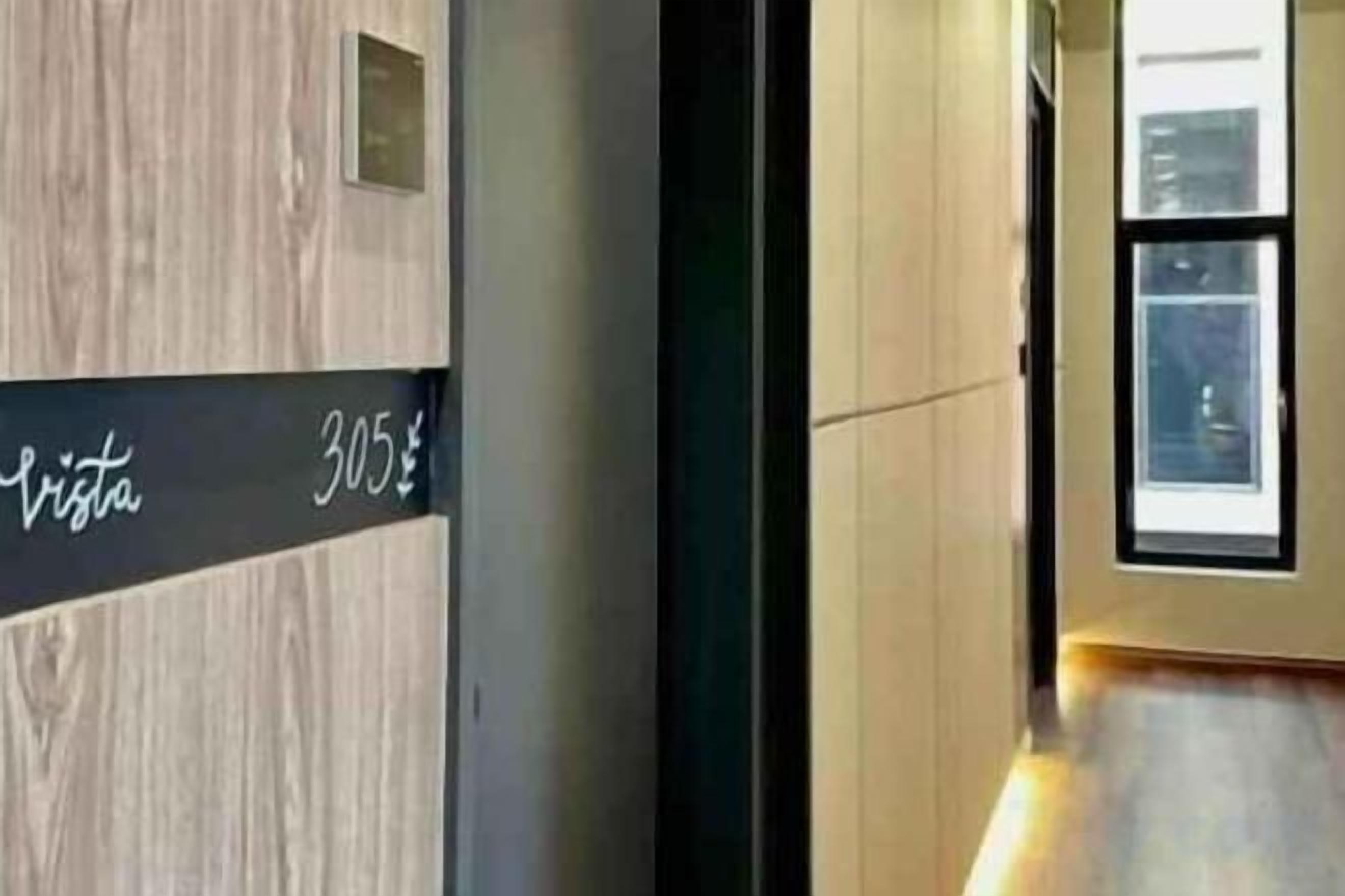 A hallway with a wooden wall and a sign indicating room number 305.