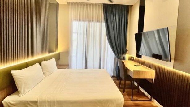 A modern hotel room with a bed, a desk, a flat-screen TV, a ceiling fan, and a window with curtains. - I-Vista Hotel (Tawau)