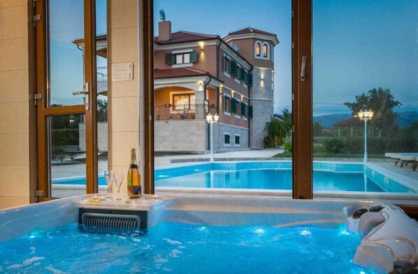 A hot tub with a view of a multi-story building and a swimming pool.