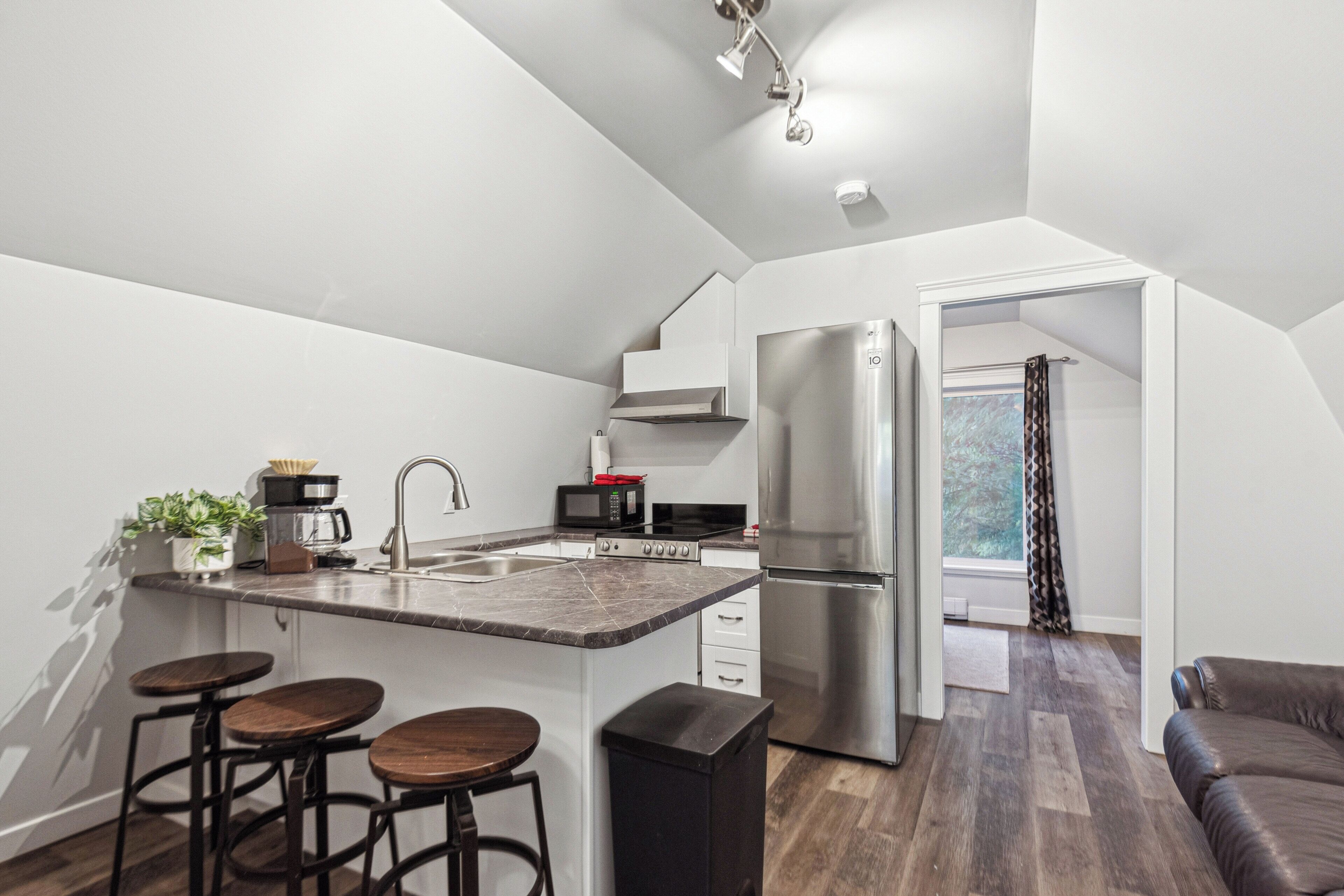 A modern kitchen with a central island, stainless steel appliances, and bar stools.