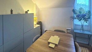 Un coin repas comprenant une table en bois, des chaises, un buffet et une fenêtre agrémentée d’une plante.