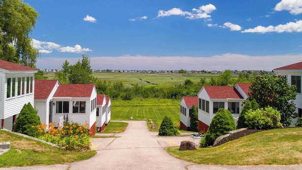 Une rangée de maisons blanches aux toits rouges, une pelouse bien entretenue et un ciel bleu azur.
