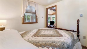 Un dormitorio con una cama grande, una ventana con persianas, un espejo y una lámpara.