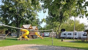 A playground with a yellow slide and a wooden playhouse.