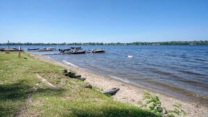 A lakeside view with boats docked, a grassy shore, and a clear sky.
