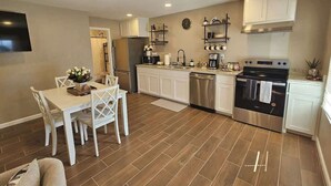 A modern kitchen with white cabinets, stainless steel appliances, and a dining area with a white table and chairs.